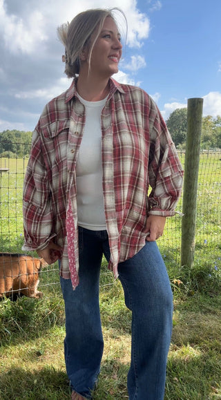 Casual fall outfit featuring an oversized red plaid flannel shirt layered over a white ribbed tank with relaxed blue jeans.