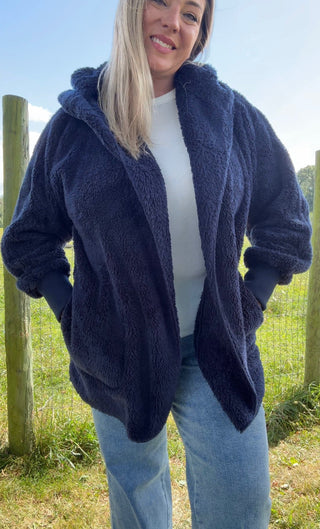 Cozy navy teddy coat with a hood and roomy front pockets—perfect for layering over a white tee and jeans for a casual-chic autumn look.