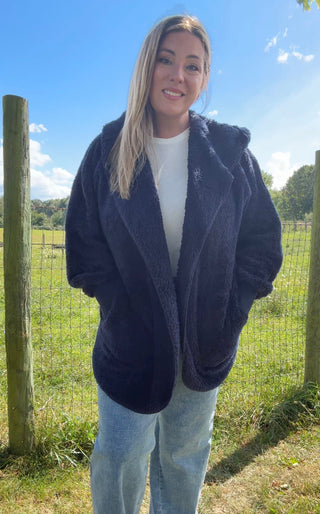Navy blue faux-fur hooded coat with a relaxed fit, styled over a white top and light-wash jeans for cozy-chic autumn layering.
