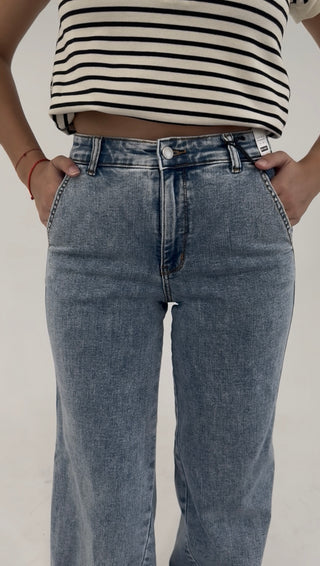 Close-up of high-rise light wash denim jeans with relaxed wide-leg fit and subtle fading detail.