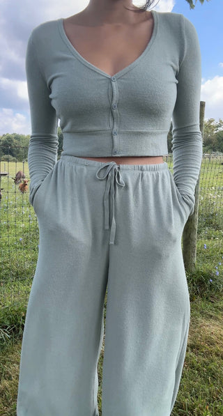 Woman in sage green lounge set with cropped button-front cardigan and drawstring wide-leg pants, soft knit boutique style.