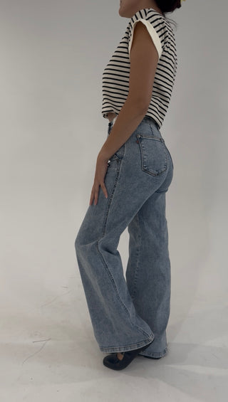 Side angle of high-waisted light wash denim jeans with a relaxed wide-leg fit and classic five-pocket styling.