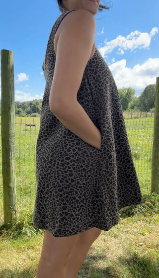 Side view of sleeveless charcoal gray swing dress with black leopard print and handy side pockets.