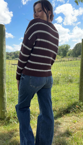 Brown ribbed sweater with white stripes styled with high-waisted blue jeans in a sunny outdoor setting.