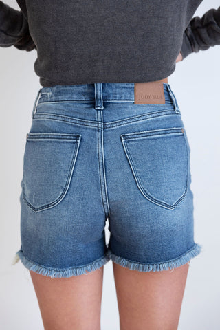 Judy Blue distressed denim shorts with frayed hem and light wash. Trendy high-rise fit for a chic and casual summer look.