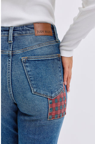 Back view of Judy Blue high-rise jeans with red and teal plaid patch detail on the pocket and leather brand label.