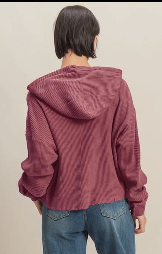Back view of cropped berry waffle-knit hoodie with relaxed fit and hood, paired with high-rise blue jeans.