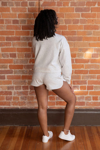 Model in a cozy gray half-zip cropped sweatshirt and matching shorts, styled effortlessly with white sneakers for a laid-back look