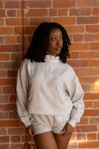 Model in a cozy gray half-zip cropped sweatshirt and matching shorts, styled effortlessly with white sneakers for a laid-back look