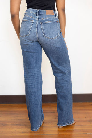 Model wearing Judy Blue straight-leg jeans in classic vintage wash with a contoured V-front waist, styled with a black bodysuit