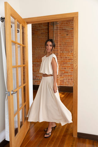 Stylish cream matching set with a sleeveless cropped top and pleated maxi skirt, perfect for a breezy, effortless look.