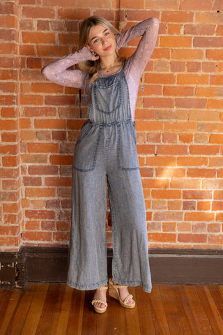 Trendy denim overalls with relaxed fit, styled over a delicate floral mesh top. Perfect for casual and layered looks.