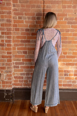 Trendy denim overalls with relaxed fit, styled over a delicate floral mesh top. Perfect for casual and layered looks.