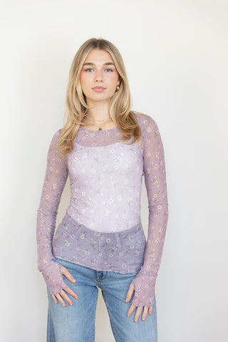 Elegant sheer lavender mesh top with dainty floral details and thumbhole sleeves, paired with classic denim for a chic, feminine look.