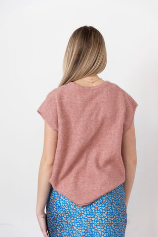 Women's blush pink knit sweater with cap sleeves and a relaxed fit. Soft, textured fabric with a slightly asymmetrical hem.