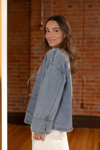 Relaxed-fit denim jacket with tie-front detailing, oversized sleeves, and front pockets for a casual yet stylish layered look.