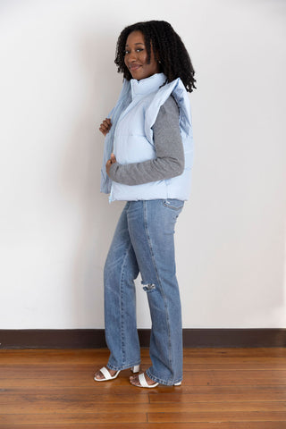 Stylish light blue puffer vest with feminine ruffle accents, perfect for layering over casual outfits for a cozy yet fashionable vibe.