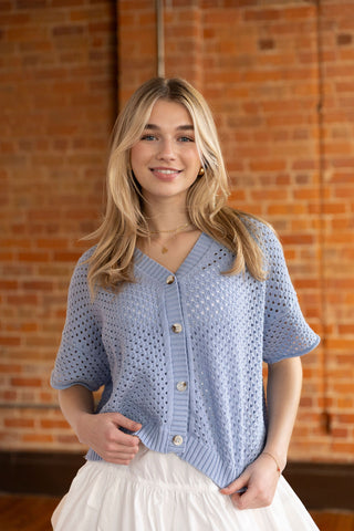 Soft blue crochet-style cardigan with button front and airy short sleeves, perfect for effortless layering.