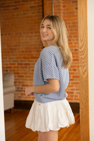 Soft blue crochet-style cardigan with button front and airy short sleeves, perfect for effortless layering.